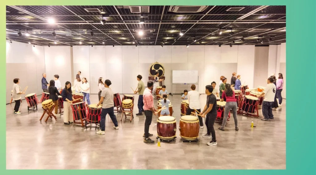 On-site corporate team building in the office meeting room, with employees focused on a taiko drum workshop activity